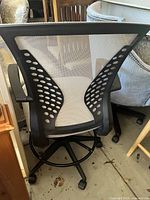 Back view of mesh office desk chair showing black frame with ventilated mesh backrest and five caster wheels at base.