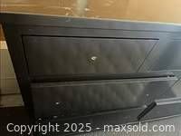 Close-up side view of black dresser showing missing drawer pulls and overall condition