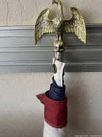 Close-up of brass eagle finial mounted atop pole wrapped with American flag fabric.