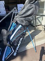 Full view of the black and blue Strata golf stand bag with shoulder straps and stand legs extended, showing bag design and structure.
