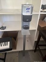 Full view of the Purell hand sanitizing station on a metal stand showing the full height and base.
