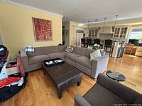 Room setting including the brown leather ottoman placed in front of a sectional sofa