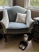 Front view of green upholstered Venetian chair with patterned wing arms and white throw pillow on the seat.