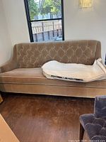Beige loveseat with button tufted backrest and curved armrests next to window.
