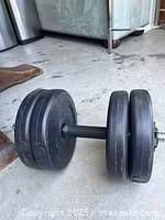 Pair of black adjustable dumbbells with metal handles and spring collar locks on concrete floor.