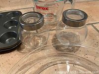 Close-up of jars, measuring cup, muffin pan, pie plate edge