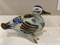 Side view of hand-painted stoneware duck showing blue and brown designs