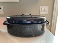 Closed view of black speckled enamel oval roasting pan with lid