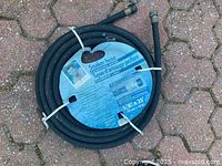 Coiled Mark Cullen soaker hose with label visible