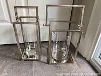 Both metal lanterns with glass inserts displayed side by side