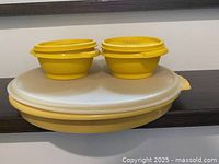 Large yellow divided dish with clear lid and two small bowls stacked on top