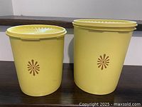 Front view of both yellow Tupperware canisters with lids