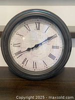Front view of round wall clock showing dial and frame