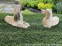 Photo showing side view of two Afghan Hound garden sculptures placed on grass with natural background highlights the size difference and detail of each sculpture.