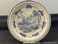 Full view of the blue and white cabinet plate showing the central rural scene of people in an early automobile, winding road, trees, bushes, and a church or schoolhouse with a border of vintage car illustrations and text.