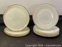 Two stacks of Fire King milk glass dinner plates, showing white glossy surface with gold trim around edges, plates arranged to show front surface and side profile.