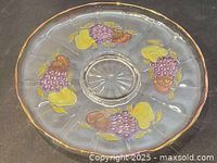 Overhead view showing the full round tray with colorful painted fruit design at four points on the surface and a central circular depression.