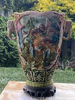 Front angled view showing hand painted landscape with elephant head handle on the side