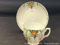 Front angle of the teacup on the saucer showing the floral pattern and square handle