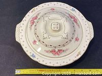 Top-down view of the covered tureen showing the ornate lid with embossed patterns, hand-painted pink roses, and a yellow ruler indicating width of 10.25 inches.