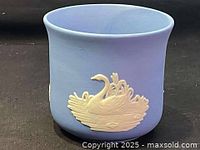 Light blue ceramic plant pot with cream-colored raised relief of a swan on one side.