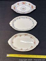 Top-down view of three Royal Albert oval relish dishes with a ruler showing approximate width of 8.5 inches in front, floral patterned ceramic dishes in varying colors.