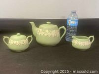 Full set of green tea pot, sugar bowl, and creamer with white floral relief decoration shown with water bottle for scale