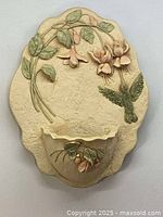 Full front view of vintage wall pocket vase showing floral and hummingbird design with pocket for flowers.
