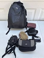 Overall view of six bags including Samsonite black backpack and five smaller camera or accessory pouches