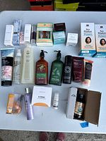 Overview of various bathroom products displayed on white table including creams, shampoos, lotions, and sprays, some still boxed.