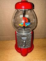 Front view of the gumball candy machine showing red metal top and base, glass globe with PlayStation logo in multiple colors on front.