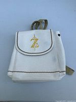Front view of the mini purse showing white faux leather with Zelda emblem gold detail on flap and brown decorative stitching.