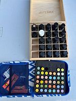 doTERRA wood box with essential oil bottles and open blue zippered carrying case with foam insert showing bottle slots and mesh pockets