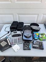 Full view of all electronic items on a table including calculators, speakers, portable CD player, handheld games, and VR accessories