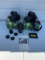Two Fujifilm FinePix S2 Pro DSLR camera bodies with lenses mounted, plus upright telephoto lens, manual, caps and PPA pouch displayed on boxes.