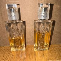 Front view of two partially full travel spray bottles of Givenchy Hot Couture Eau de Parfum showing amber liquid and decorative design.