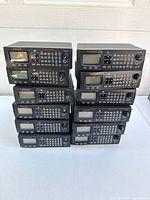 Twelve black GRECOM PSR-410 scanners stacked in two columns on table