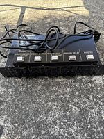 Top front view of Ibanez UE405 multi effects unit showing the footswitches and control knobs with cables attached, placed on concrete.