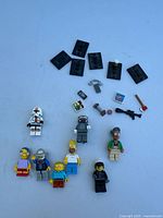 All 9 minifigures and accessories arranged on a flat surface showing figures plus six black base plates and small accessory pieces.