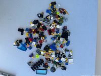 Top-down view of all Lego mini figures and parts spread out on a light surface.