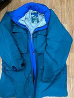 Front and inside view of vintage LL Bean large tall men's jacket folded on floor showing blue and green colors, zipper, buttons, and pockets.