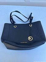 Full view of the black Michael Kors handbag showing its size, shape, and strap design on a white background.