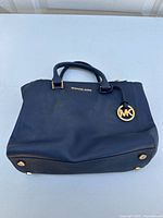 Top front view showing the Michael Kors logo, handles, and MK charm on the purse