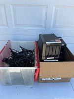 Overall lot showing two bins: one filled with cables, the other with NAS units