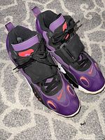 Top angle showing pair of Nike Air Max Speed Turf shoes in night purple with black and orange details on a carpeted surface.