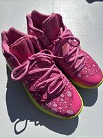 Front angle view of the pink basketball shoes showing lacing, toe box, and upper design.