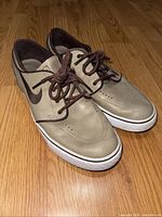 Side and front angled view of Nike Zoom Stefan Janoski OG skate shoes in Khaki and Boulder Brown showing upper, laces, and outsole wear