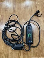 Full view of the coiled Ford OEM EV charging cable showing connector ends and inline controller box with Ford logo and green plug symbol.