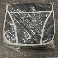Front view of the sealed black PS2 crossbody carrying case with gray trim and embroidered PS2 and PlayStation logos visible through the plastic wrapping.