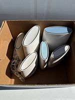 Top down shot of multiple Orbi router satellite units of various sizes in a box, showing the design and layout.